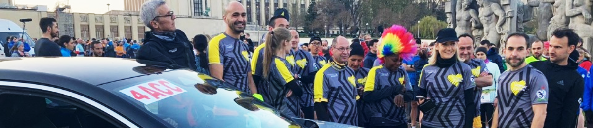 Photographie des participants de la Course du Coeur, entouré d'un public de supporters.