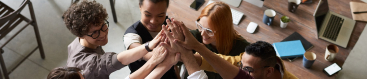Photographie de collaborateurs tendant et joignant leurs mains en cercle.