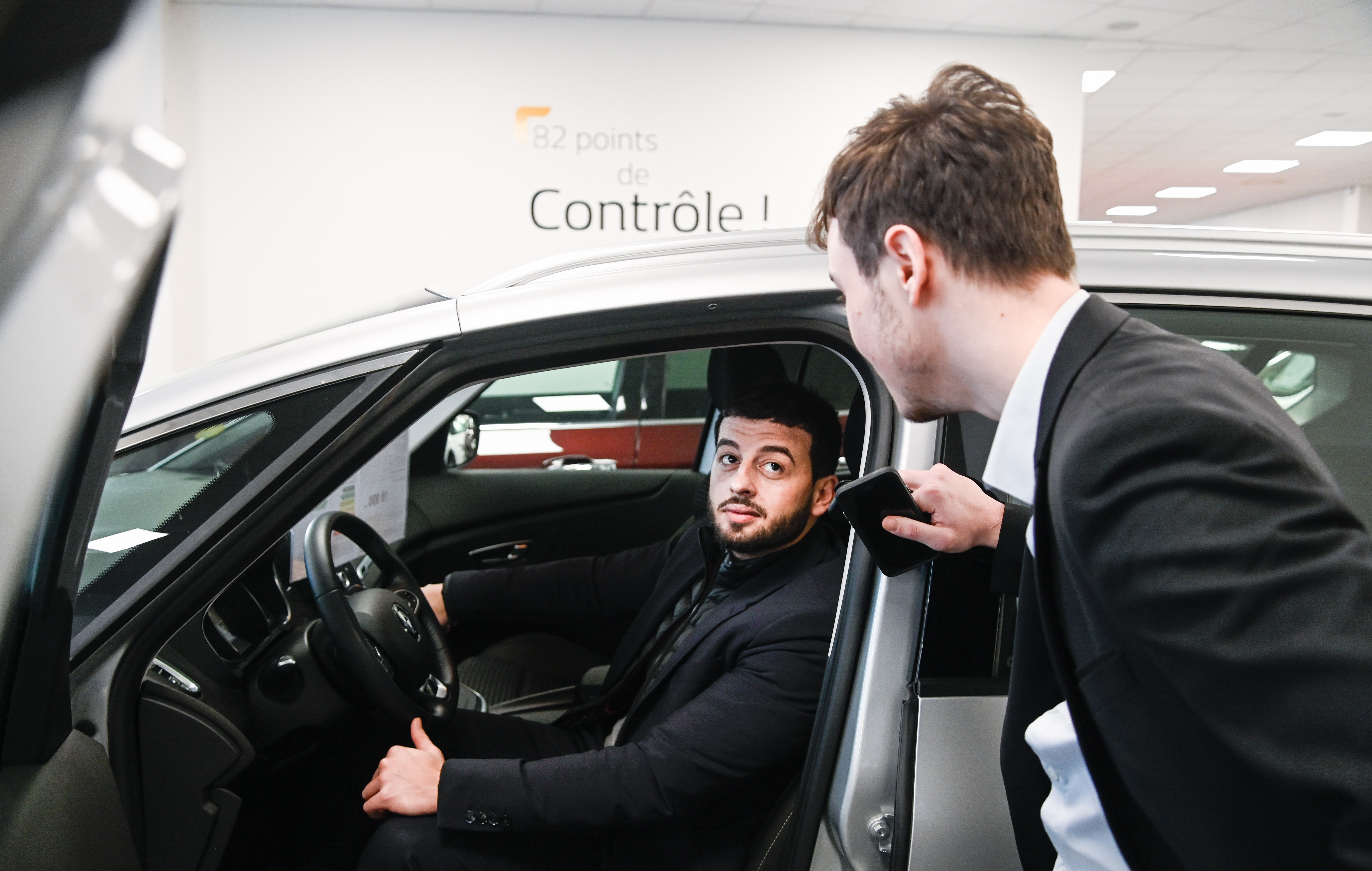 Photographie d'un vendeur conseillant un client à l'intérieur d'un véhicule.